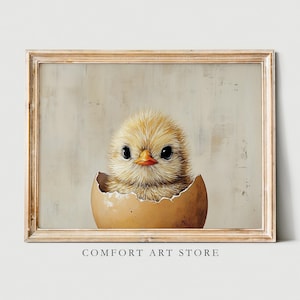 May include: A framed print of a fluffy yellow chick hatching from an egg. The chick has large black eyes and an orange beak. The artwork is set against a neutral background. The text "COMFORT ART STORE" is at the bottom of the frame.