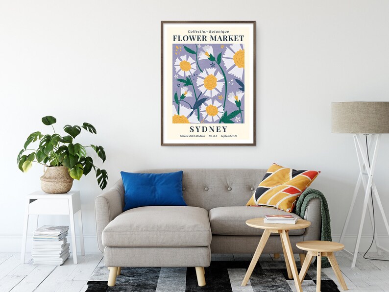 May include: A framed art print featuring a floral design with daisies in white and yellow against a lavender background. The print includes the text "Flower Market Sydney" and is displayed in a living room setting.