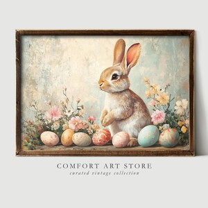 Puede incluir: Una ilustraci&oacute;n vintage de un conejo marr&oacute;n sentado entre flores rosas y amarillas y huevos de Pascua coloridos. La imagen tiene un fondo texturizado y desgastado.