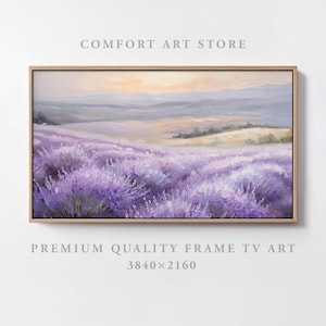 May include: A painting of a lavender field with a soft, purple hue. The field is in the foreground, with rolling hills and a distant sunset in the background. The painting is framed in a light wood frame.