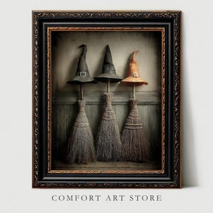 May include: A framed print depicting three witch hats on broomsticks. The hats are black and orange, with silver buckles. The brooms have straw bristles. The frame is black with gold detailing. The text "COMFORT ART STORE" is at the bottom.