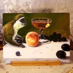 Può includere: Un dipinto di natura morta con una scimmia, una pesca, uva e un bicchiere di vino. La scimmia sta guardando il bicchiere di vino. Il dipinto è su un cavalletto di legno.