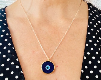 Puede incluir: Un collar de cadena dorada con un colgante de ojo turco azul y blanco. El colgante es redondo y tiene un borde dorado.