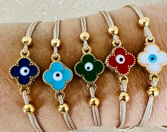 May include: Five adjustable bracelets with a gold chain and a clover-shaped charm with an evil eye design. The charms are in different colors: blue, turquoise, green, red, and white.