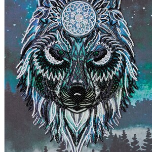 May include: A detailed beaded artwork of a wolf's head, featuring intricate patterns in shades of blue, teal, black, and white. The wolf's eyes are green, and a circular design adorns its forehead. The background depicts a starry night sky and a forest silhouette.