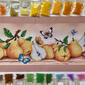 May include: A diamond painting kit featuring a still life of pears and butterflies. The image shows a completed painting with yellow and brown pears, green leaves, and colorful butterflies. Small bags of beads are arranged above and below the painting.