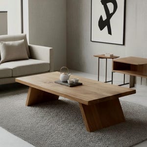 Puede incluir: Un sal&oacute;n moderno con una gran mesa de centro rectangular de madera con patas anguladas. Una tetera y tazas blancas est&aacute;n sobre una bandeja oscura. Un sof&aacute; y una alfombra de color gris claro complementan la mesa. Una obra de arte abstracta enmarcada cuelga en la pared.