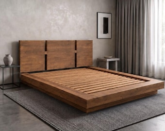 Può includere: Una struttura letto a piattaforma dal profilo basso realizzata in legno marrone medio con venature visibili. La testiera presenta tre pannelli verticali separati da strette fessure. La base del letto è composta da doghe orizzontali.