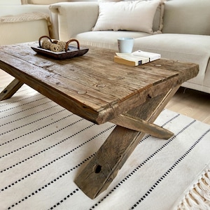 May include: A set of three ceramic mugs with a speckled, cream-colored glaze. Each mug features a different hand-painted design: a blue and green leaf, a yellow flower, and a red berry. The mugs have a simple, rounded shape.