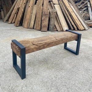 May include: A rustic wooden bench with a black metal frame. The bench is made from reclaimed wood and has a natural, weathered finish. The metal frame is sturdy and provides support for the bench.