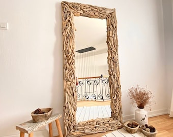 May include: A large, rectangular mirror with a unique frame made of driftwood. The frame is a natural brown colour and has a rustic, organic look. The mirror is reflecting a room with a white tiled floor and a black metal railing.