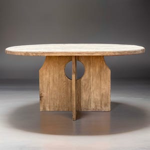 May include: A round wooden table with a unique, open base design. The table top is made of natural wood with a light brown finish. The base features two circular cutouts and a cross-shaped support.