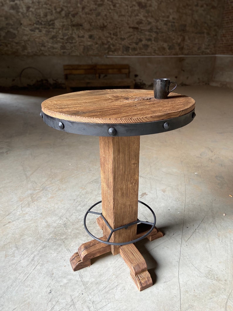 May include: A round wooden table with a black metal band around the edge and a black metal base. The table has a rustic look and is perfect for a small space.