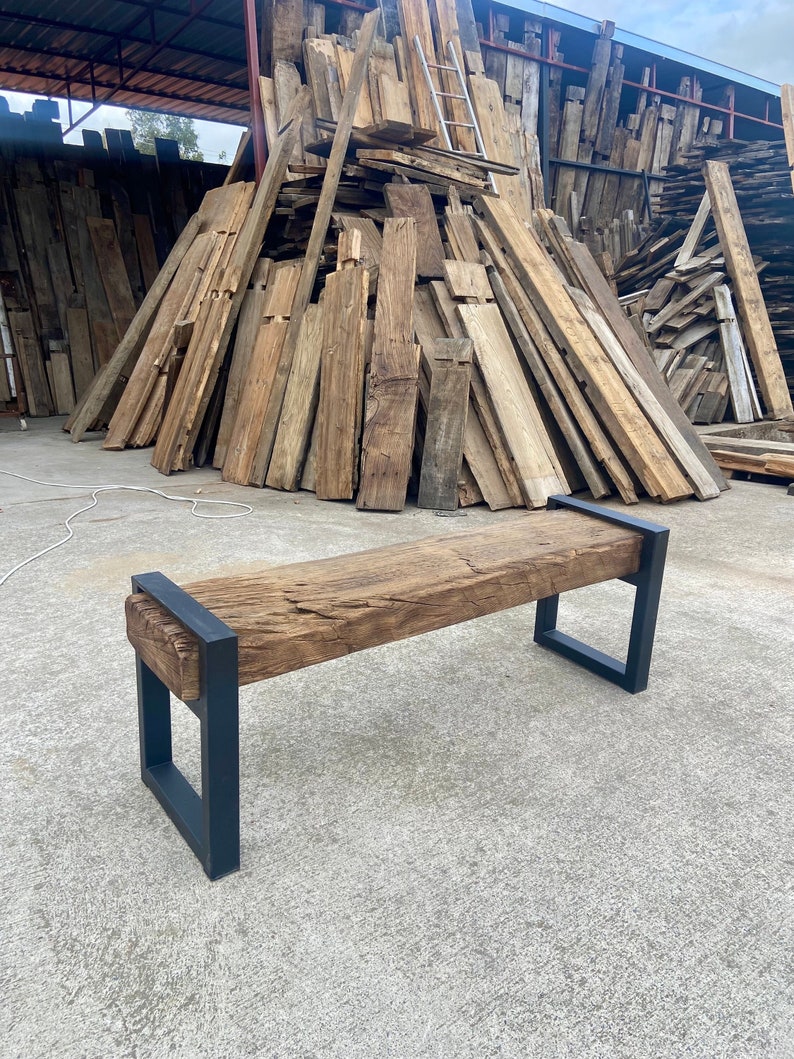 May include: A rustic wooden bench with a black metal frame. The bench is made from reclaimed wood and has a natural, weathered finish. The metal frame is sturdy and provides support for the bench.