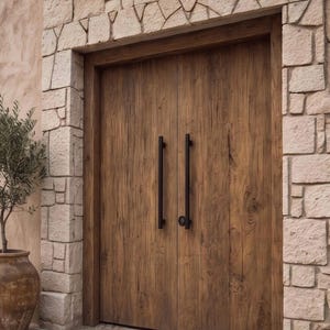May include: A set of double doors made of brown wood with a visible grain pattern, featuring two long, vertical black metal handles. The doors are framed by light-colored, irregular stone blocks that form an archway above the entrance.