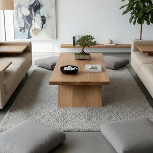 Puede incluir: Sal&oacute;n moderno con dos sof&aacute;s beige, mesas auxiliares de madera, mesa de centro de madera clara, cojines grises y alfombra gris clara. Un bons&aacute;i y objetos decorativos adornan la mesa.