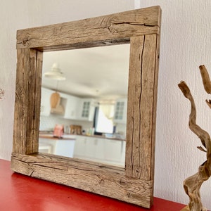 Puede incluir: Un espejo cuadrado con un marco de madera r&uacute;stico. El marco est&aacute; hecho de madera recuperada con un acabado marr&oacute;n natural. El espejo refleja una habitaci&oacute;n con paredes blancas y una encimera de madera.