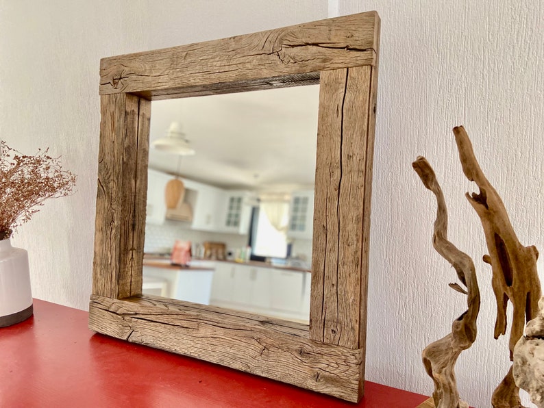 Puede incluir: Un espejo cuadrado con un marco de madera r&uacute;stico. El marco est&aacute; hecho de madera recuperada con un acabado marr&oacute;n natural. El espejo refleja una habitaci&oacute;n con paredes blancas y una encimera de madera.