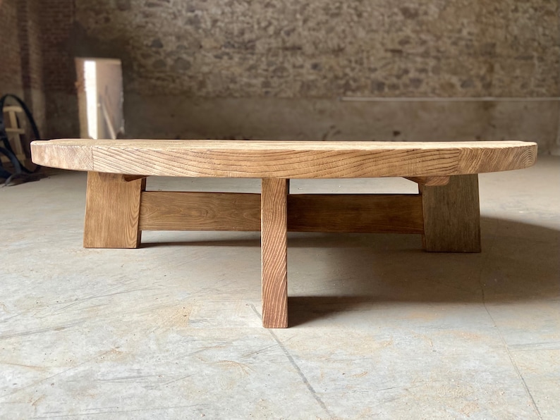 Pu&ograve; includere: Un tavolino da caff&egrave; rotondo in legno con finitura naturale e design semplice e moderno. Il tavolino ha quattro gambe leggermente inclinate e un piano largo e piatto.