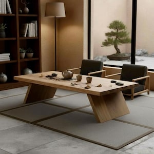 Puede incluir: Una mesa baja de madera clara con patas anguladas, situada en una habitaci&oacute;n minimalista. La mesa est&aacute; puesta con una tetera, tazas y accesorios para el t&eacute;. Dos sillones oscuros est&aacute;n colocados cerca, y un bons&aacute;i es visible a trav&eacute;s de una gran ventana.