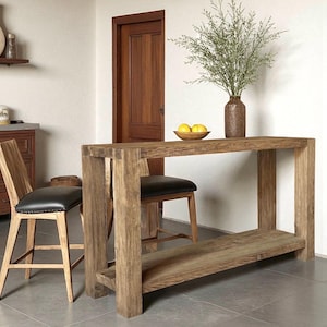 Peut inclure: Un &icirc;lot de cuisine en bois rustique avec une &eacute;tag&egrave;re inf&eacute;rieure, associ&eacute; &agrave; deux tabourets de bar en bois avec des si&egrave;ges en cuir noir. Un vase avec de la verdure et un bol de citrons sont pos&eacute;s sur l'&icirc;lot. La pi&egrave;ce a une porte en bois et un meuble.