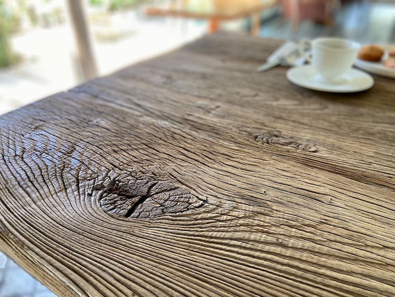 May include: Close-up of a rustic wooden table top with a knot in the wood. The wood has a natural, weathered finish.
