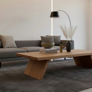 Puede incluir: Sal&oacute;n moderno con sof&aacute; gris, mesa de centro de madera y alfombra gris oscura. Los elementos decorativos incluyen un jarr&oacute;n con hierba de la pampa y un cuenco.