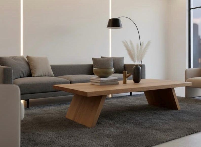 Puede incluir: Sal&oacute;n moderno con sof&aacute; gris, mesa de centro de madera y alfombra gris oscura. Los elementos decorativos incluyen un jarr&oacute;n con hierba de la pampa y un cuenco.