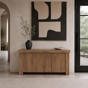 Peut inclure: Un buffet rectangulaire en bois dot&eacute; de trois portes verticales et d'un plateau &eacute;pais. Sur le buffet se trouvent un vase noir contenant des branches feuillues vertes et un petit bol peu profond de couleur claire. Une grande &oelig;uvre murale carr&eacute;e est suspendue au-dessus.