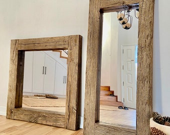 May include: Two rustic wooden framed mirrors with a natural wood finish. The larger mirror is standing upright and the smaller mirror is lying flat on the floor. Both mirrors have a rectangular shape and are made of reclaimed wood.