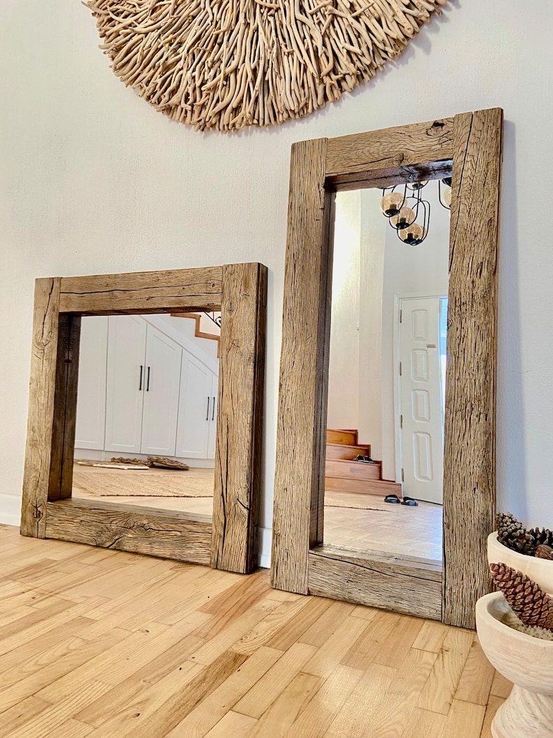 Puede incluir: Dos espejos con marco de madera r&uacute;stica con un acabado de madera natural. El espejo m&aacute;s grande est&aacute; de pie y el espejo m&aacute;s peque&ntilde;o est&aacute; acostado en el suelo. Ambos espejos tienen una forma rectangular y est&aacute;n hechos de madera recuperada.
