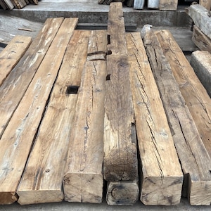 May include: A collection of reclaimed wood beams, showing the natural grain and knots of the wood. The beams are various lengths and widths, and have a rustic, weathered look.