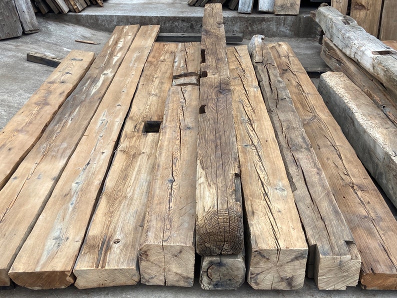 May include: A collection of reclaimed wood beams, showing the natural grain and knots of the wood. The beams are various lengths and widths, and have a rustic, weathered look.