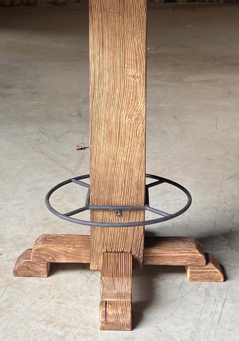 May include: A wooden table base with a metal ring around the center post. The base has four legs with a decorative design.