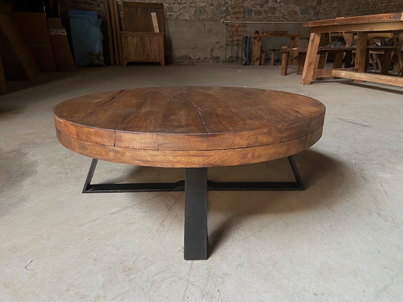 K&ouml;nnte beinhalten: Ein runder Holz-Couchtisch mit dunkelbrauner Oberfl&auml;che und einem schwarzen Metallgestell. Der Tisch hat einen einzigartigen, rustikalen Look und passt perfekt in ein modernes oder industrielles Wohnzimmer.
