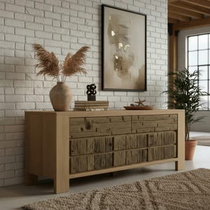 May include: A light wood-tone sideboard with six drawers, featuring a rustic, reclaimed wood design on the drawer fronts. The sideboard is in a room with a brick wall, a framed artwork, and decorative items on top.