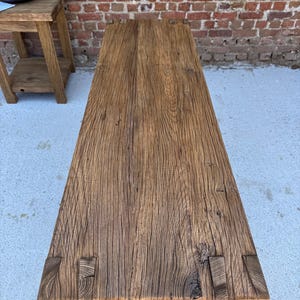 Peut inclure: Une console rectangulaire en bois rustique avec une finition naturelle et vieillie. La table pr&eacute;sente un grain de bois visible et des assemblages &agrave; queue d'aronde aux coins. Elle est en bois massif et poss&egrave;de une &eacute;tag&egrave;re inf&eacute;rieure.