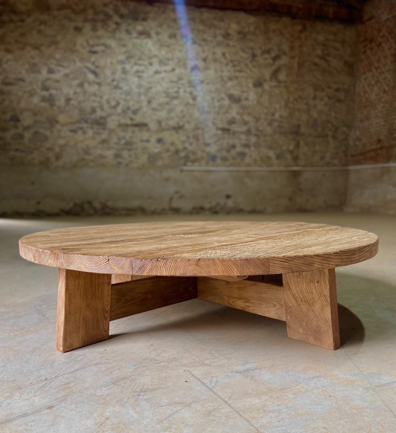Pu&ograve; includere: Un tavolino da caff&egrave; rotondo in legno con una finitura in legno naturale e un design semplice e moderno. Il tavolo ha un piano largo e piatto e una base robusta con quattro gambe.