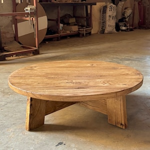 Pu&ograve; includere: Un tavolino da caff&egrave; rotondo in legno con una finitura in legno naturale e quattro gambe. Il tavolo &egrave; realizzato in legno riciclato e ha un aspetto rustico.