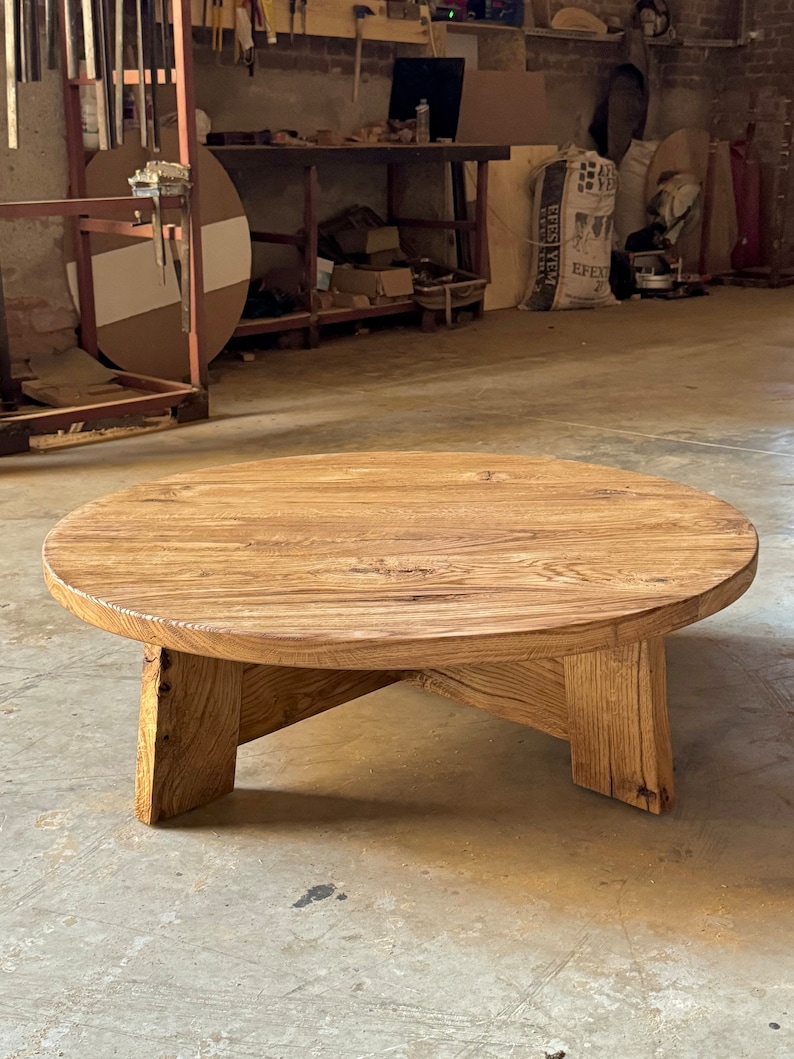 Pu&ograve; includere: Un tavolino da caff&egrave; rotondo in legno con una finitura in legno naturale e quattro gambe. Il tavolo &egrave; realizzato in legno riciclato e ha un aspetto rustico.