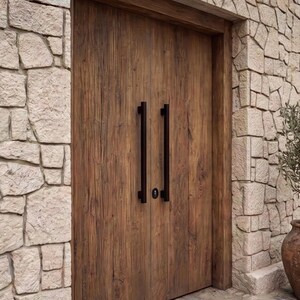 May include: A set of double doors made of dark brown wood with a visible grain pattern. The doors feature two long, vertical, matte black metal handles positioned in the center, along with a small, circular black lock mechanism between them.