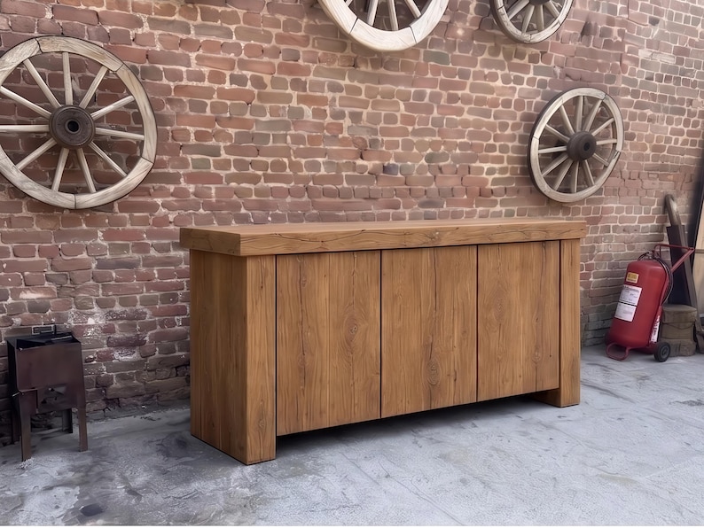 Peut inclure: Un buffet rectangulaire en bois dot&eacute; d'un plateau &eacute;pais et massif ainsi que de trois portes de placard verticales. Le meuble est fabriqu&eacute; en bois brun clair avec un grain visible et une finition lisse, reposant sur une base plate.