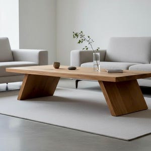 Puede incluir: Una mesa de centro rectangular de madera con patas anguladas. La mesa es de madera clara y tiene un acabado natural. Un peque&ntilde;o jarr&oacute;n, una taza y un libro est&aacute;n sobre la mesa. La mesa mide 152 cm de largo.
