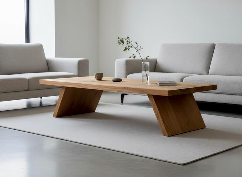 Puede incluir: Una mesa de centro rectangular de madera con patas anguladas. La mesa es de madera clara y tiene un acabado natural. Un peque&ntilde;o jarr&oacute;n, una taza y un libro est&aacute;n sobre la mesa. La mesa mide 152 cm de largo.