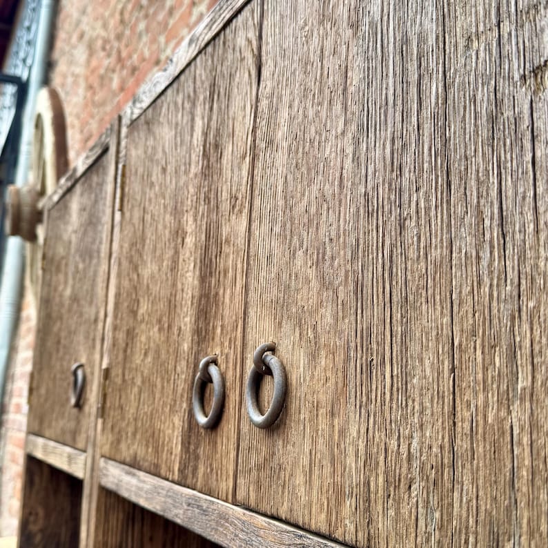 Puede incluir: Primer plano de un armario de madera con dos puertas. Las puertas tienen tiradores de anillo de metal y est&aacute;n hechas de madera recuperada con un acabado r&uacute;stico.