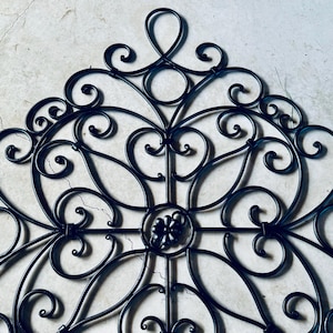 May include: Black metal wall decor with a decorative, intricate design featuring swirls and scrolls.