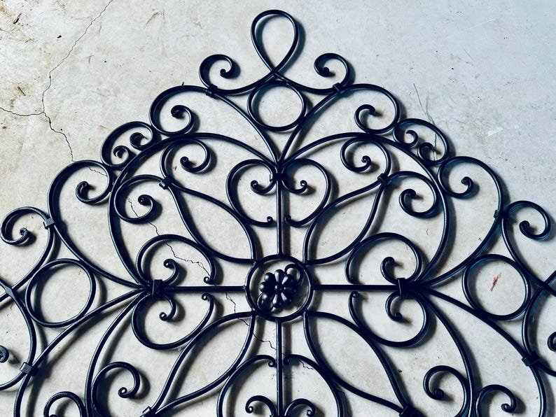 May include: Black metal wall decor with a decorative, intricate design featuring swirls and scrolls.