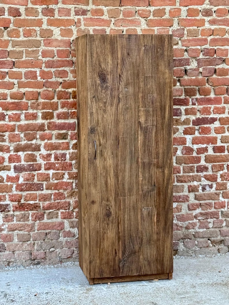 Pode incluir: Um arm&aacute;rio de madeira alto com uma &uacute;nica porta. O arm&aacute;rio &eacute; feito de madeira marrom escura com um acabamento r&uacute;stico. A porta est&aacute; fechada e tem um design simples.