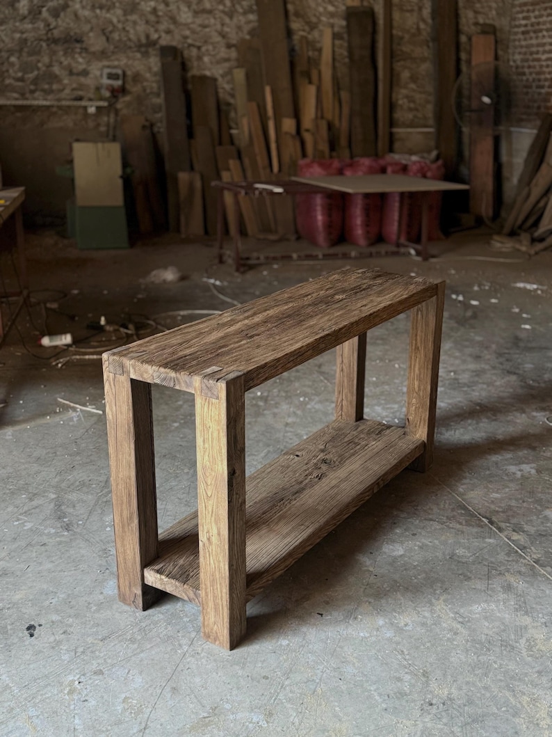 K&ouml;nnte beinhalten: Ein rustikaler Holz-Konsolentisch mit einem einzigen Regal. Der Tisch ist aus recyceltem Holz gefertigt und hat eine nat&uuml;rliche Oberfl&auml;che. Der Tisch ist 122 cm lang, 41 cm breit und 76 cm hoch.