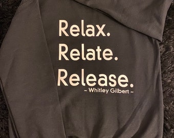Op de afbeelding: Zwart sweatshirt met witte tekst die "Relax. Relate. Release. ~Whitley Gilbert~" zegt.